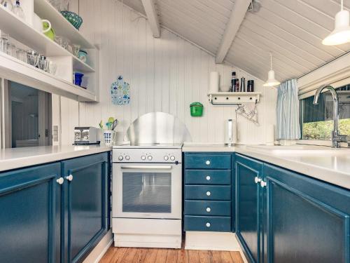 uma cozinha com armários azuis, um fogão e um lavatório em 6 person holiday home in Haarby em Brunshuse