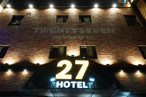 a hotel sign in front of a brick building at 27 Hotel in Anyang
