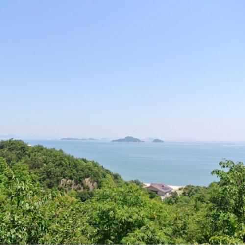 a view of the ocean from a hill with trees at Kyukamura Setouchi-Toyo in Saijo