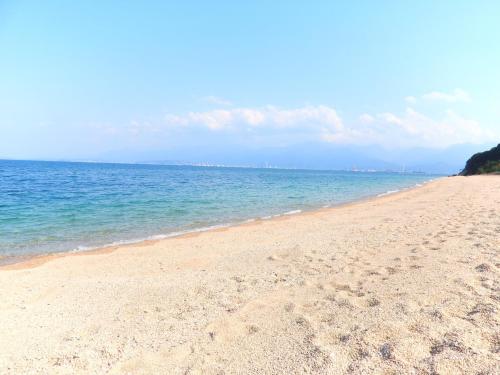a sandy beach with the ocean in the background at Kyukamura Setouchi-Toyo in Saijo