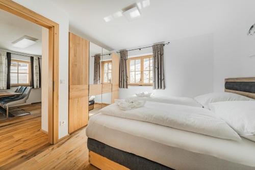 a white bedroom with a large bed and a chair at Dachstein West Apartment 1B in Russbach am Pass Gschütt