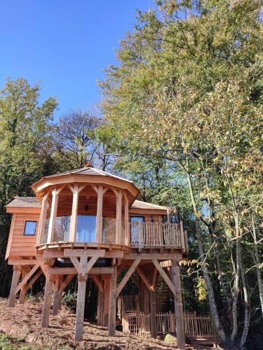ein großes Holzbaumhaus mit einer Terrasse in der Unterkunft Le Domaine des Roches' L in Gommené