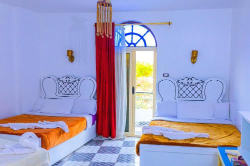 sypialnia z 2 łóżkami i drzwiami na patio w obiekcie Onaty Ka Guest House w mieście Aswan