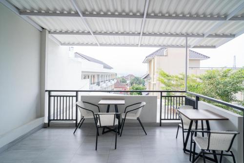 a patio with tables and chairs on a balcony at Urbanview Hotel Bubusini Batu by RedDoorz in Batu