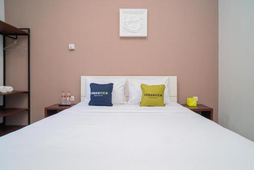 a bedroom with a white bed with two pillows at Urbanview Hotel Bubusini Batu by RedDoorz in Batu
