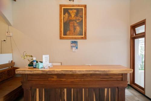 un bancone in legno in una stanza con un dipinto sul muro di Urbanview Hotel Bubusini Batu by RedDoorz a Batu