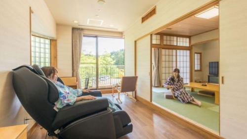 two women sitting in chairs in a room with a mirror at Kyukamura Oku-Musashi in Hanno