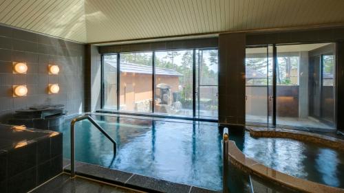 a large indoor swimming pool with a large window at Kyukamura Retreat-Azumino-Hotel in Azumino