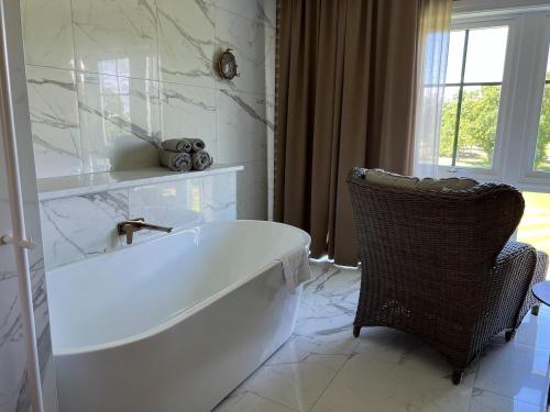 La salle de bains est pourvue d'une baignoire blanche et d'une chaise. dans l'établissement Ombergs Golf Resort, à Ödeshög