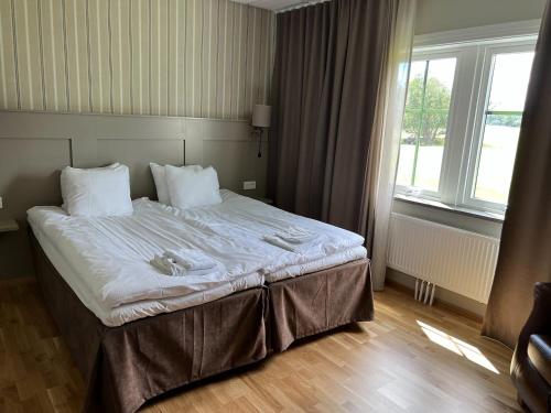 Cette chambre comprend un grand lit et une grande fenêtre. dans l'établissement Ombergs Golf Resort, à Ödeshög