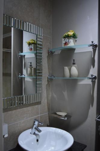 een badkamer met een wastafel en een spiegel bij Accommodation Front - Deluxe 6 Sleeper with Rooftop Pool in Durban