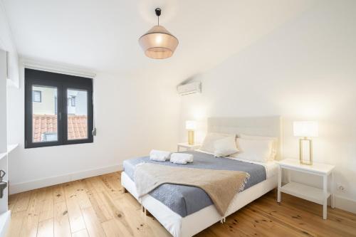 ein weißes Schlafzimmer mit einem Bett und einem Fenster in der Unterkunft Warm and Cozy Parquet Flooring Apartment in Almada in Almada