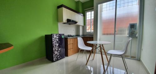 cocina con paredes verdes, mesa y sillas en REG GUESTHOUSE en Tanjungredep