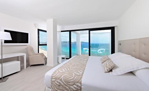a white bedroom with a bed and a chair at Iberostar Cala Millor - Adults Only in Cala Millor