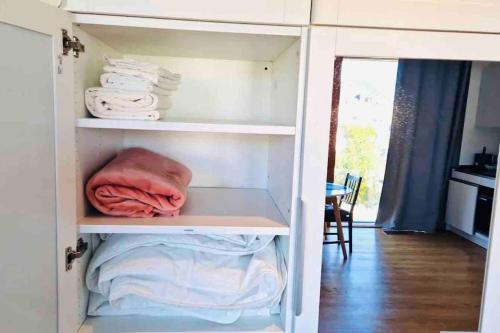 ein Schrank mit weißen Regalen und Handtüchern in der Unterkunft Lovely New Studio in Kirchberg - G in Luxemburg (Stadt)