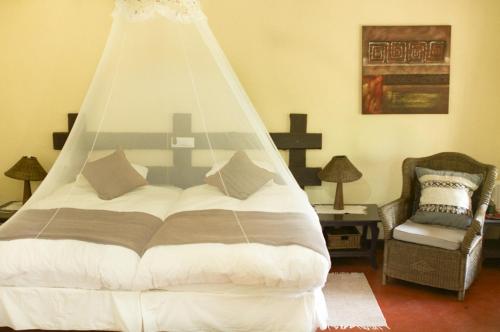 a bed with a canopy in a room with a chair at Woodlands Lilongwe in Lilongwe