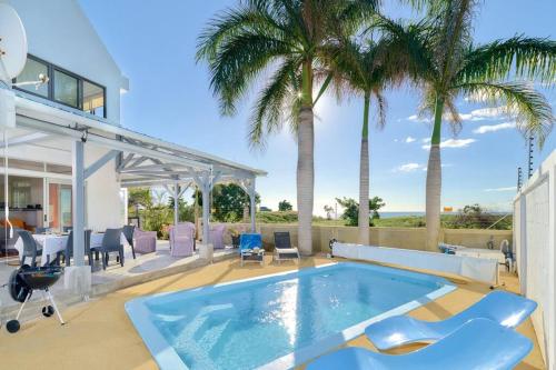 een huis met een zwembad en palmbomen bij Côte Ouest - VUE IMPRENABLE SUR LA MER - VILLA BELIFAGE BLEUE avec Piscine Privative in Albion