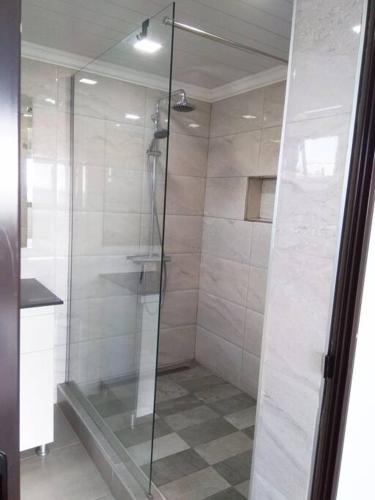 une douche avec une porte vitrée dans une salle de bain dans l'établissement Côte Ouest - VUE IMPRENABLE SUR LA MER - VILLA BELIFAGE BLEUE avec Piscine Privative, à Albion