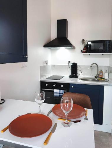 a kitchen with a table with two plates and wine glasses at Le Relax in Albert