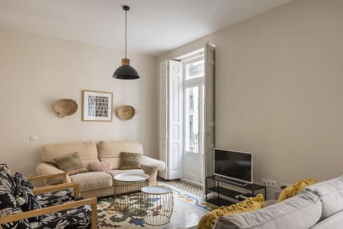 a living room with a couch and a tv at Macflats Ayuntamiento in Valencia