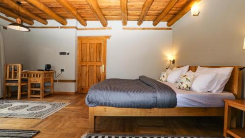 a bedroom with a bed in a room with a table at Dakpa House Ladakh in Ranbirpura