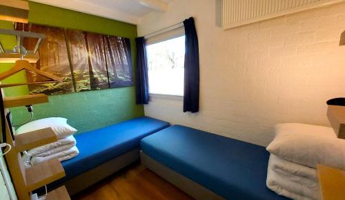 een kleine kamer met een blauwe bank en een raam bij Vakantiehuis Saffier in Simpelveld