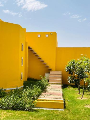 a yellow building with a staircase in front of it at Anand Bagh Resort & Spa by Ananta in Sālāsar