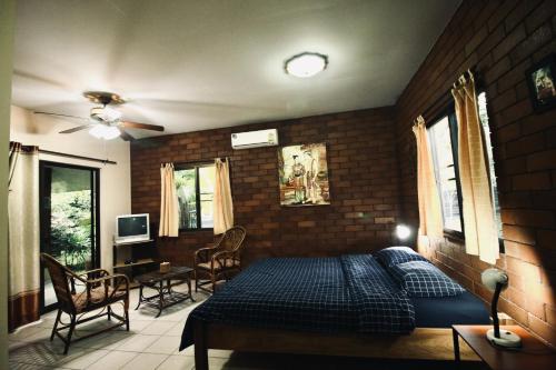 a bedroom with a bed and a brick wall at Khoom Kam Kaew in Phrao