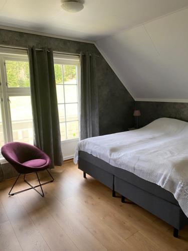 Schlafzimmer mit einem Bett, einem Stuhl und Fenstern in der Unterkunft The house of Mattis in beautiful Innvik in Innvik