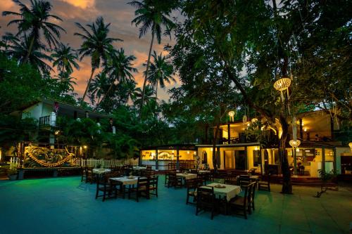 ein Restaurant mit Tischen, Stühlen und Palmen in der Unterkunft La La Land Resort Goa by Spicy Mango in Palolem