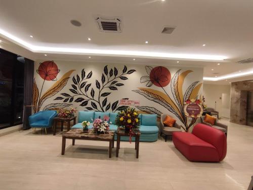 a lobby with couches and flowers on the wall at Kesuma Front One Boutique Palembang in Palembang