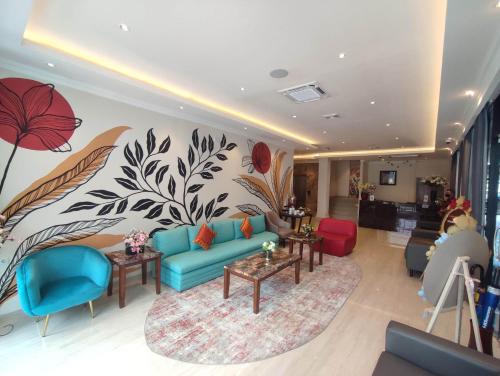 a living room with a blue couch and flowers on the wall at Kesuma Front One Boutique Palembang in Palembang