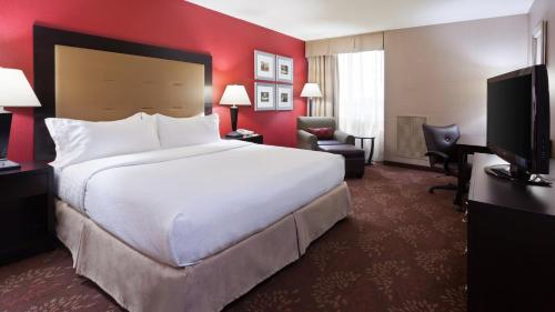 um quarto de hotel com uma grande cama branca e paredes vermelhas em Holiday Inn Cincinnati Airport, an IHG Hotel em Erlanger