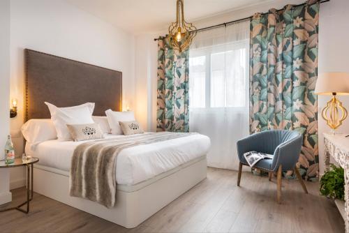 Un dormitorio con una cama y una silla y una ventana. en Casa Triana 1888 Suites by Época, en Sevilla
