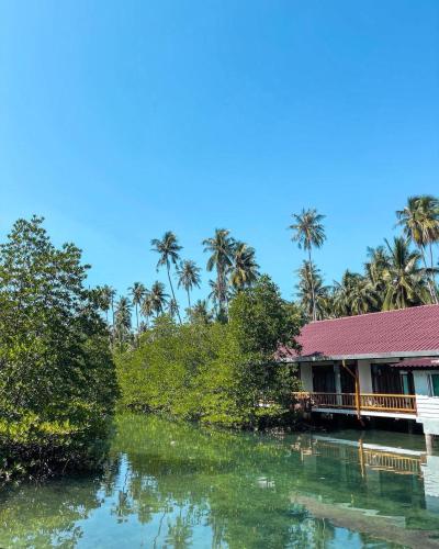 a house next to a river with palm trees at À La Koh Kood Resort in Ko Kood