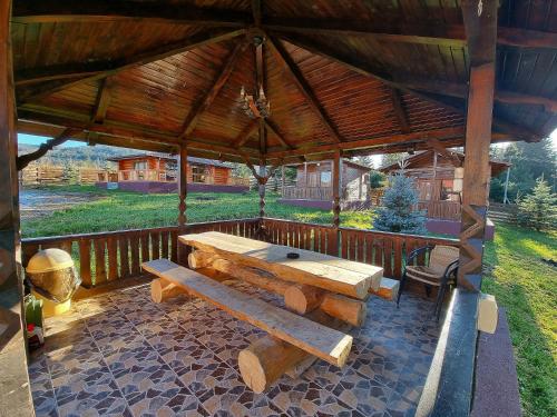 a wooden pavilion with a picnic table on a patio at Casa Dragomir in Plaiu Şarului