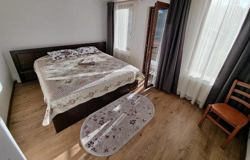 a bedroom with a bed and a chair and a window at Casa Dragomir in Plaiu Şarului