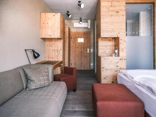 シュラートミンクにあるファルケンシュタイナー ホテル シュラートミンクのソファとベッドが備わる木製の壁の客室です。