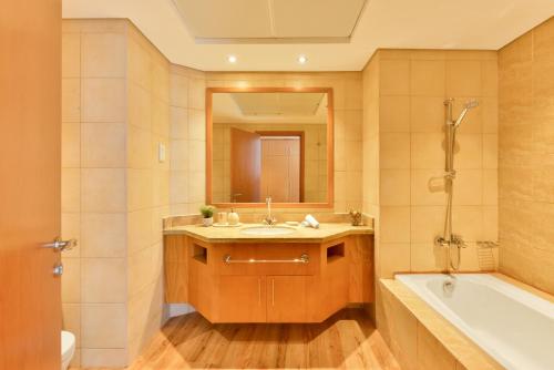 bagno con lavandino, vasca e specchio di Luxury JBR I Al Fattan Full Sea View I Free 5 star Beach Resorts Access a Dubai