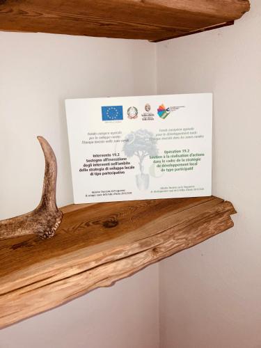a sign on a wall with a wooden shelf at Lo Micho - Le Four des Alpes in Rhemes-Saint-Georges