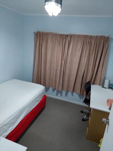 a room with a bed and a desk and a window at Wendy's Holiday Home in Auckland