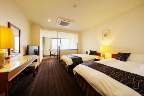 una camera d'albergo con 2 letti e una scrivania di Ryochiku Bettei a Beppu