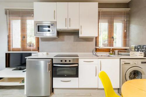 a kitchen with white cabinets and a table with a yellow chair at Apartamento Valverde II in Potes