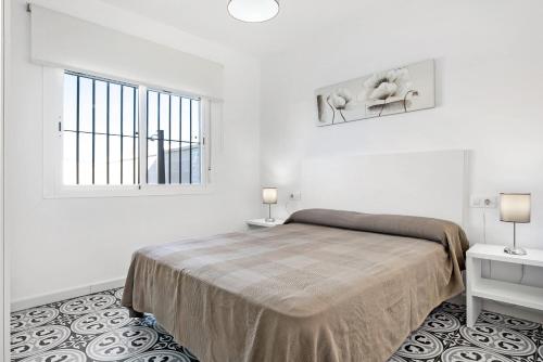 a white bedroom with a bed and a window at Casa Pablo in Conil de la Frontera