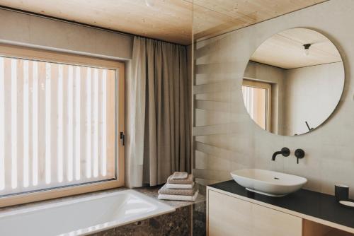 a bathroom with a tub and a sink and a mirror at HALWINA Hideaway in Sibratsgfäll