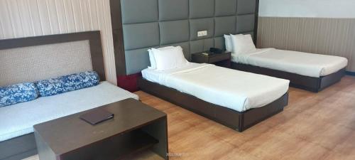 ein Hotelzimmer mit 2 Betten und einem Tisch in der Unterkunft The Green Garden Retreat, Dooars in Sukhani