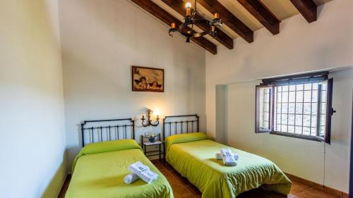 two beds in a room with green sheets at Fuente de la Gitana Rute by Ruralidays in Rute