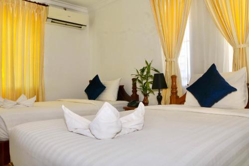a bedroom with two beds with blue and white pillows at The Blanc Residence in Siem Reap