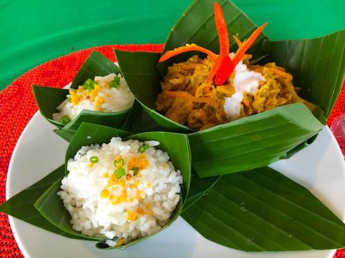 a plate of food with rice and vegetables in leaves at The Blanc Residence in Siem Reap
