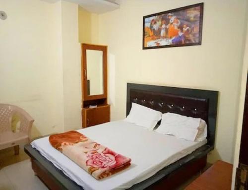 een slaapkamer met een bed met witte lakens en een spiegel bij Hotel Goyal, Mansa in Mānsa